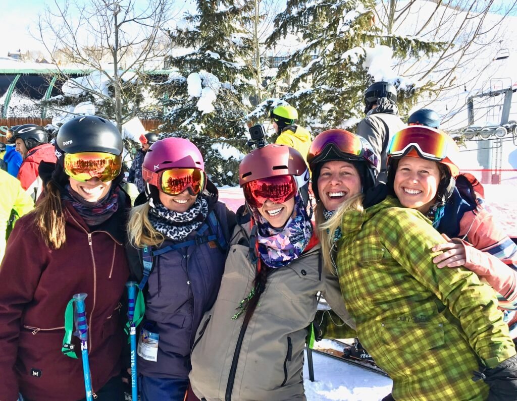women with snowboards smiling together on a snowy mountain ski trip